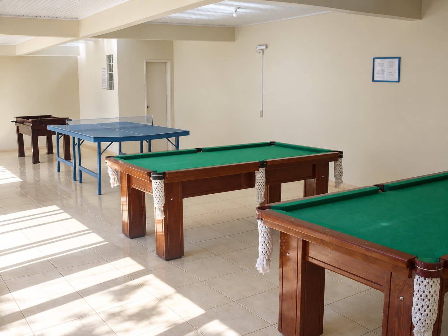 Sala de jogos com mesas de sinuca, tênis de mesa e pebolim